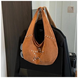 Close-up of brown suede hobo bag with silver star stud detailing on a black blazer