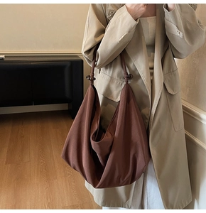 Close-up of large brown suede tote bag featuring unique knotted shoulder straps and beads