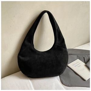 Detailed close-up of a black suede crescent bag in a stylish lifestyle setting