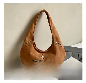 Close-up of brown suede hobo bag featuring silver rivets and half-moon structure