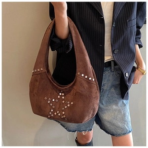 Detail of suede shoulder bag with metallic rivets forming a star pattern decoration