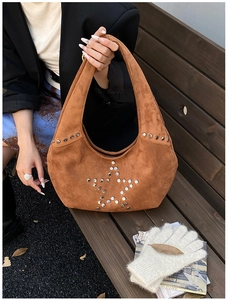 Detail of brown suede shoulder bag with silver star rivets in an autumn street setting