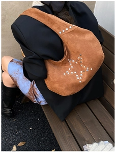 Detailed back view of a brown suede hobo bag featuring silver star rivet decorations