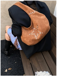 Brown suede hobo bag with silver star rivets shown from a side view on a shoulder