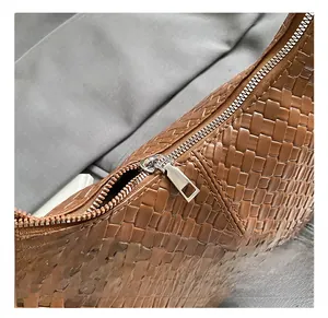 Detail of brown woven leather texture with high-quality silver metal zipper on crossbody bag