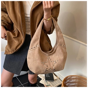 Detail of suede shoulder bag with silver rivet star patterns in khaki earth tone