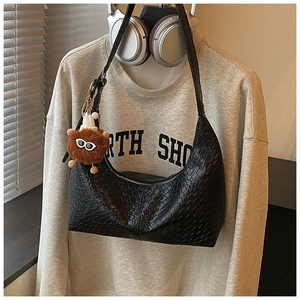 Black woven shoulder bag with monster charm and headphones styled on casual sweatshirt