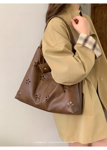 Detail of retro tote bag featuring intricate floral hollow-out carving and faux leather texture
