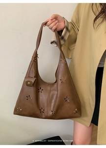 Detail of retro brown leather tote with laser-cut floral patterns and a small matching pouch