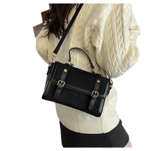 Sac messager noir mat avec boucles dorées et bandoulière porté par un mannequin