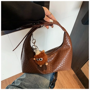 Detail of woven texture on dark brown hobo bag with a cute monster plush charm