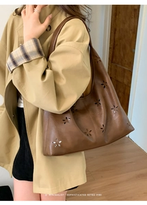 Detail view of large dark brown retro tote bag with laser-cut floral patterns and inner pouch