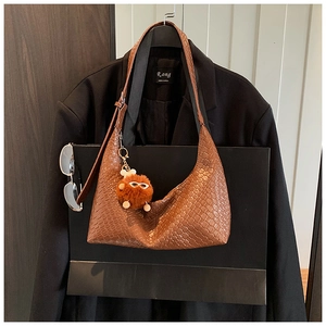 Detailed view of brown woven texture hobo bag with a cute orange plush charm detail