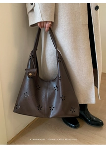 Detail of vintage dark brown tote bag with laser-cut floral patterns and small side pouch