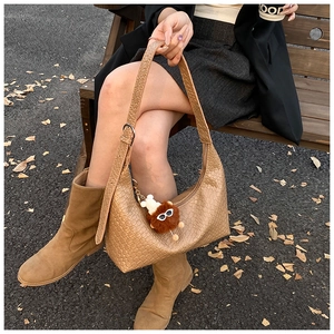 Detail of woven light brown leather hobo bag with wide strap and cute plush charm