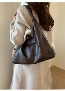 Detail of dark brown tote bag featuring floral laser-cut hollow pattern and leather texture