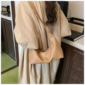 Detail of woven texture khaki crossbody bag with wide strap on a model side view