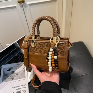 Brown leather handbag with leopard print and woven handles in a lifestyle office setting