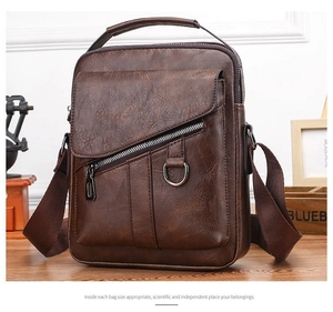 Brown textured leather crossbody bag detail with front zipper and top handle on wood desk