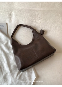 Detail of dark brown leather tote with hollow floral patterns and retro matte texture