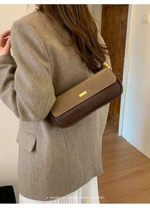 Detailed side view of minimalist brown leather baguette bag with golden metal hardware