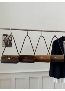 Close-up of leopard print and solid matte leather shoulder bags with gold hardware