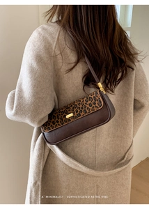 Detail of retro underarm bag with leopard print flap and gold metallic buckle