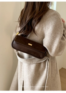 Close-up of retro leopard style baguette bag with gold buckle on oatmeal wool coat
