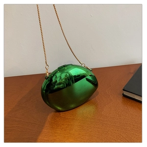 Detail of green metallic evening bag with pebble shape and gold chain strap