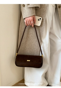 Detail of retro brown baguette bag with gold buckle on beige coat outfit