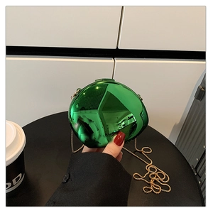 Detail of emerald green electroplated spherical bag with golden chain strap handle
