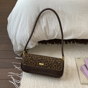 Detail of dark brown leather underarm bag with leopard print flap and gold hardware