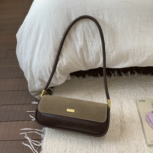 Detail of underarm bag featuring brown leather, green suede and gold buckle
