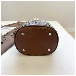 Dettagli borsa a secchiello in pelle marrone con chiusura a perla e piedini in metallo