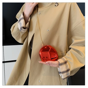 Close-up of metallic red evening clutch with gold chain and glossy mirror finish