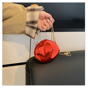 Detailed close-up of a bright red metallic sphere clutch bag with a golden chain strap