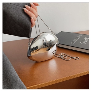 Close-up of a silver oval metal clutch bag with mirror finish and acrylic chain strap