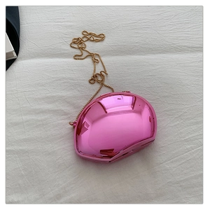 Top view of pink mirror-finish metal clutch with golden ball chain on white cloth