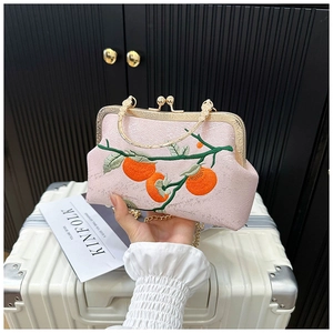 Close-up of pink embroidered handbag with persimmon pattern and vintage gold metal clasp