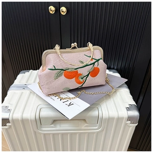 Detail of pink embroidered handbag with persimmon pattern and vintage metal frame clasp