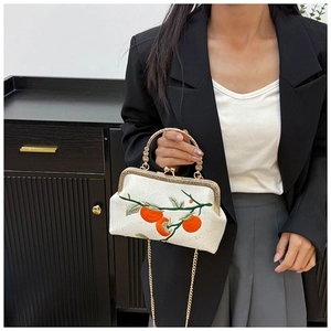 Detail of vintage white silk handbag with orange persimmon embroidery and gold metal handle