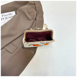 Detail of vintage embroidery bag with orange patterns and golden metal kiss lock closure