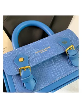 Detail of blue faux snakeskin handbag with gold buckle and embossed brand lettering