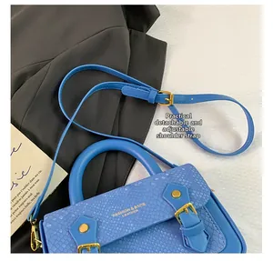 Detail of blue faux leather crossbody bag with snake skin pattern and adjustable strap