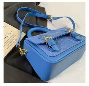 Detailed side view of blue snake skin texture handbag with golden buckles and top handle