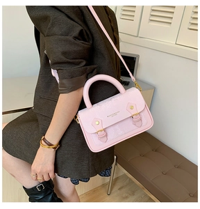 Detail of pink snake-embossed small crossbody bag with gold buckles and thick top handle