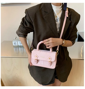 Detail of pink snake-embossed mini square bag with golden hardware and adjustable strap