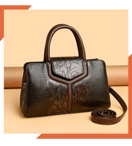 Dettaglio della borsa marrone scuro con motivo a rose a rilievo e pelle texture lucertola