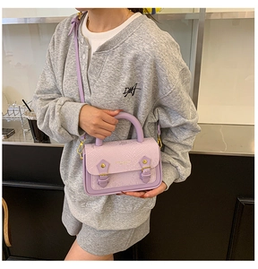 Detail view of light purple crossbody bag with snakeskin texture and gold hardware details