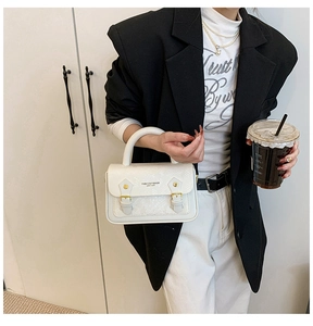 Close-up of snake skin texture and gold buckle details on this white minimalist handbag